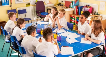 Children sitting around a table in a classroom doing work