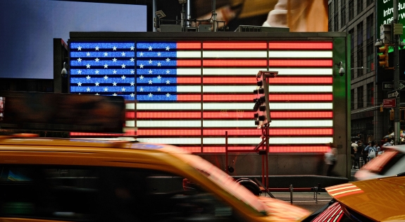 Digital sign depicting US flag with yellow cabs in the foreground.